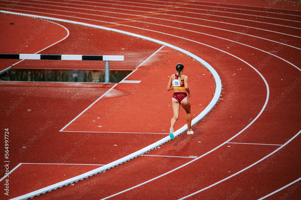 Obraz premium Determined female athlete in the midst of a distance race on track. Perfect for promoting perseverance, athleticism and physical fitness
