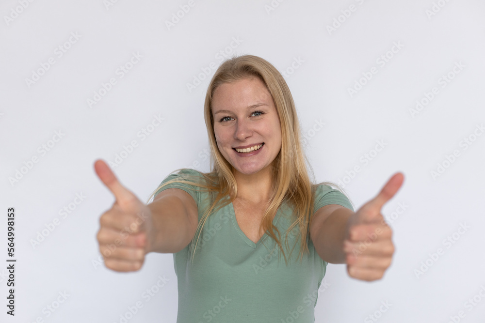 Optimistic woman showing thumbs up. Young female model making like gesture with both hands. Portrait, studio shot, support, quality concept Optimistic woman showing thumbs up. Young female model making like gesture with both hands. Portrait, studio shot, support, quality concept