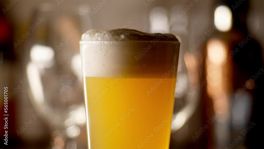 Close up of craft Beer being poured in to a pint glass, light background Close up of craft Beer being poured in to a pint glass, light background