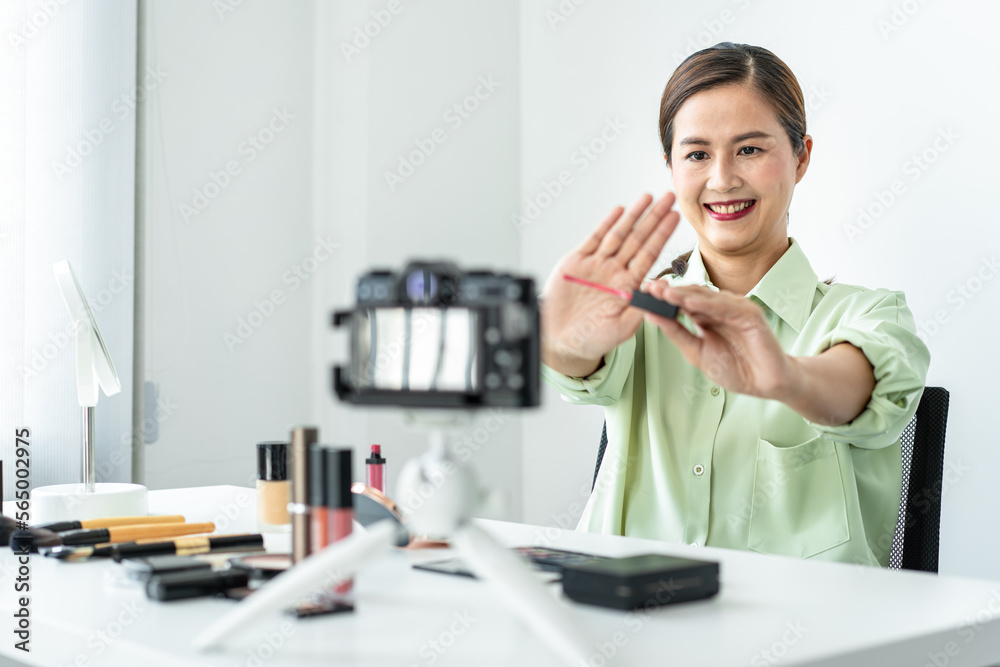 Woman blogger is showing present make up tutorial beauty cosmetic review product and broadcast live streaming video to social network teaching online on the camera screen Woman blogger is showing present make up tutorial beauty cosmetic review product and broadcast live streaming video to social network teaching online on the camera screen