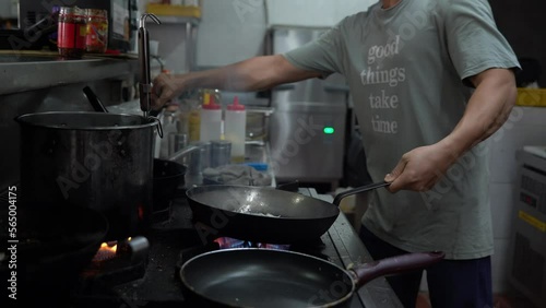 Local Asian street food culture, professional chef stir frying fresh ingredients with burning flames and aromatic smokes, authentic and traditional hawker centre, handheld close up shot.