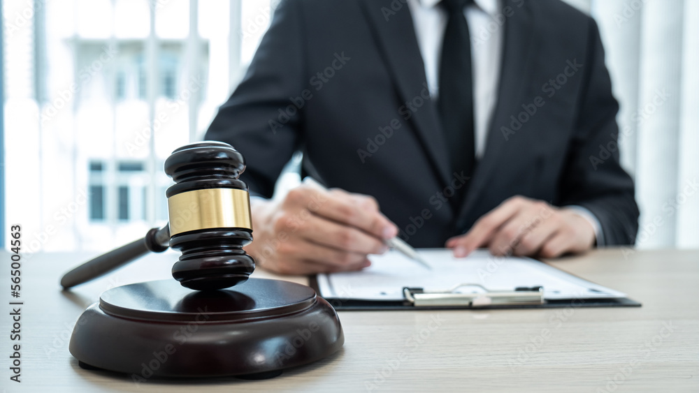 A male lawyer or notary working with contract papers, book and wooden gavel on table in courtroom, Law and Legal services concept A male lawyer or notary working with contract papers, book and wooden gavel on table in courtroom, Law and Legal services concept
