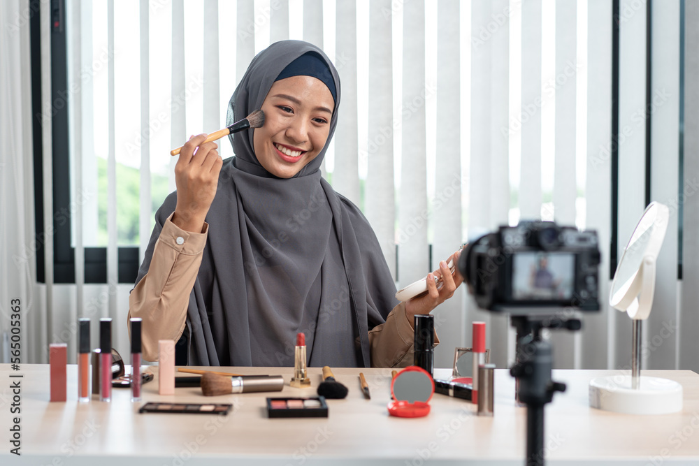Woman muslim blogger is showing present make up tutorial beauty cosmetic review product and broadcast live streaming video to social network teaching online on the camera screen Woman muslim blogger is showing present make up tutorial beauty cosmetic review product and broadcast live streaming video to social network teaching online on the camera screen