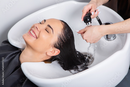 professional hairdresser washing hair of young woman in beauty salonю Beautiful young woman with long black hair in a beauty salon.