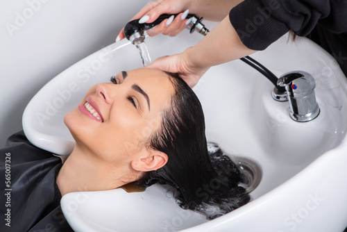 professional hairdresser washing hair of young woman in beauty salonю Beautiful young woman with long black hair in a beauty salon.
