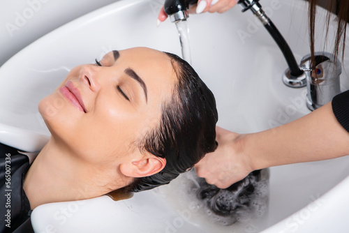 professional hairdresser washing hair of young woman in beauty salonю Beautiful young woman with long black hair in a beauty salon.