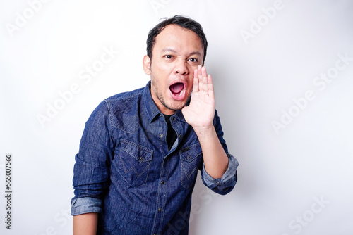 Young handsome man wearing a blue shirt shouting and screaming loud with a hand on his mouth. communication concept.