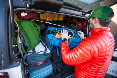 Mountain climber putting backpack into car trunk photo