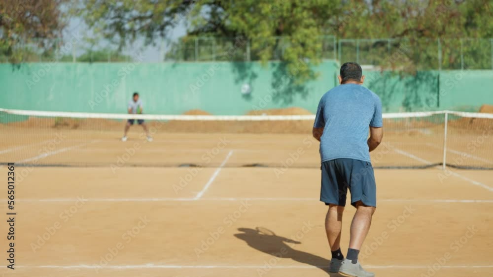 Rear view shot of senior tennis player makes foul while servicing - concept of mistakes, practising and learning Rear view shot of senior tennis player makes foul while servicing - concept of mistakes, practising and learning