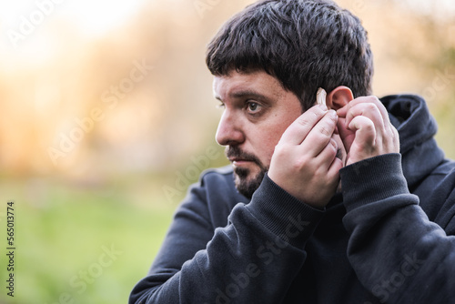 man puts the hearing aid in his ear