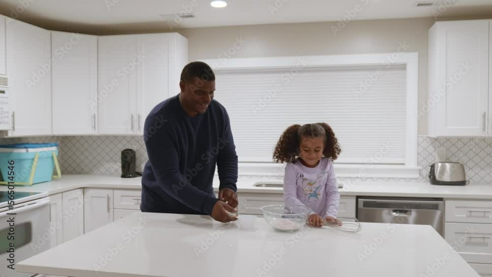 An African American father and his young daughter mix cake batter. An African American father and his young daughter mix cake batter.