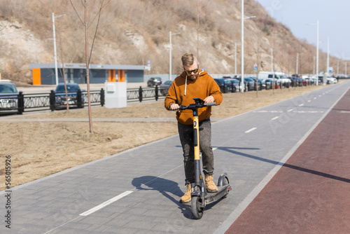 Man using smartphone after riding by electric scooter in the city. Innovative transport