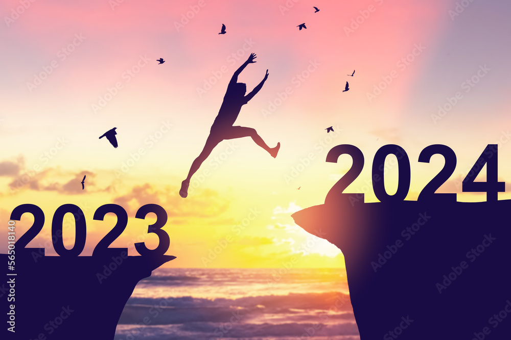 Silhouette man jumping between cliff with number 2023 to 2024 and birds flying at tropical sunset beach. Freedom challenge and travel adventure holiday concept. Silhouette man jumping between cliff with number 2023 to 2024 and birds flying at tropical sunset beach. Freedom challenge and travel adventure holiday concept.