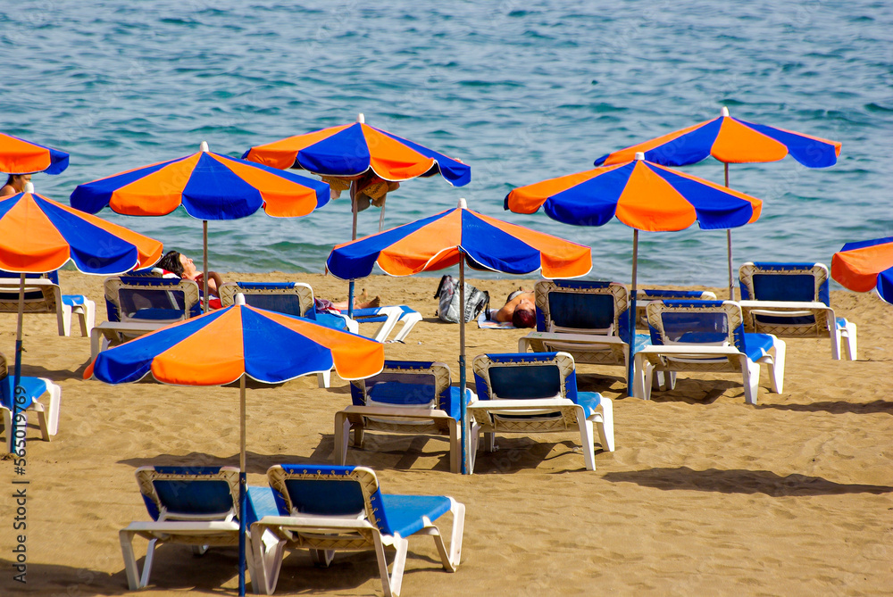 Beach scene of tourists, sunbeds and parasols overlooking the blue Atlantic Ocean, Puerto del Carmen, Lanzarote, Canary Islands, Spain. Beach scene of tourists, sunbeds and parasols overlooking the blue Atlantic Ocean, Puerto del Carmen, Lanzarote, Canary Islands, Spain.