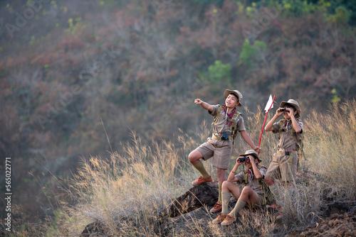 Three boy scouts exploring nature with binoculars in camp photo