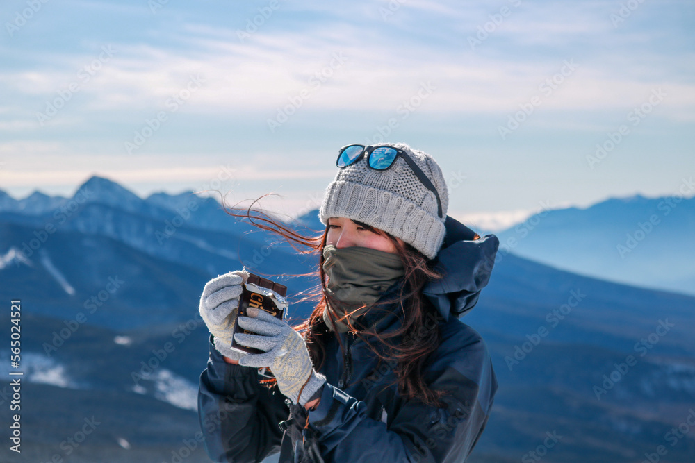 雪山でチョコを食べる女性