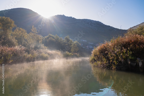 Panoramic idyllic view of water reflection in Crmnica river going to Lake Skadar in Virpazar, Bar, Montenegro, Balkans, Europe. Morning fog and haze creating mystical atmosphere in Dinaric Alps
