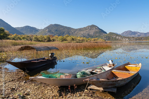 Colourful fishermen boats at lakeshore with scenic of Lake Skadar National Park in autumn near Godinje, Bar, Montenegro, Balkans, Europe. Stunning travel destination in Dinaric Alps near Albania photo