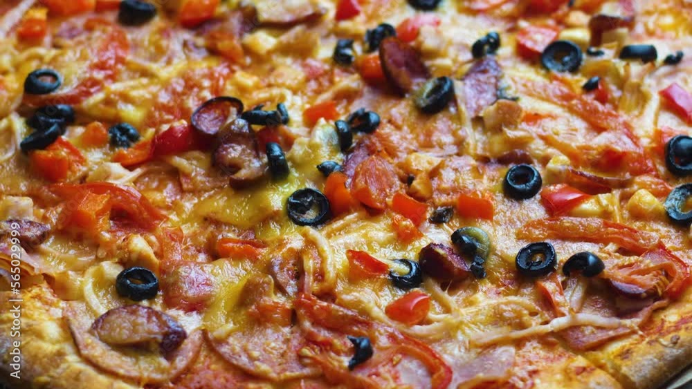 close-up appetizing fresh pizza with cheese, olives, bacon, salami rotates. selective focus. pizzeria, italian cuisine restaurant. pizza delivery. fast food for lunch