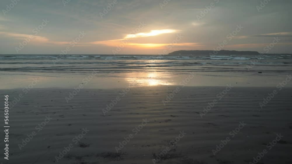 Seascape view of ocean waves crashing on a sandy beach at sunset, on a cloudy evening Seascape view of ocean waves crashing on a sandy beach at sunset, on a cloudy evening