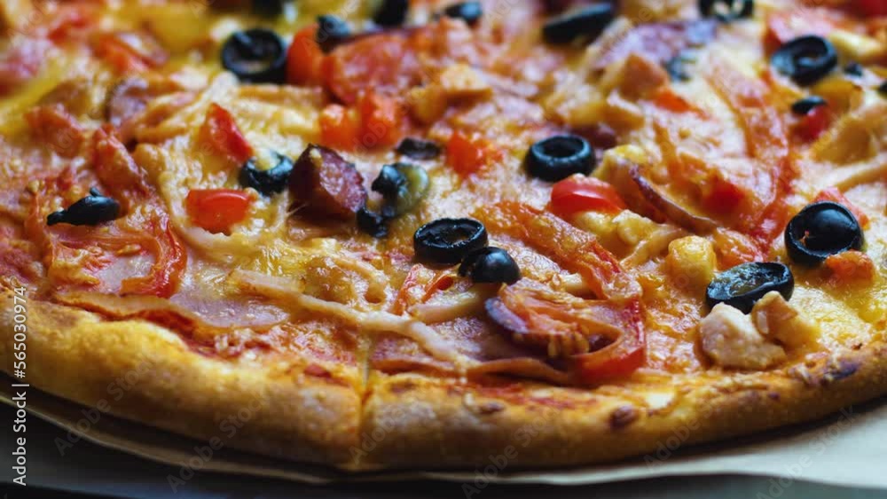 close-up appetizing fresh pizza with cheese, olives, bacon, salami rotates. selective focus. pizzeria, italian cuisine restaurant. pizza delivery. ordering food online