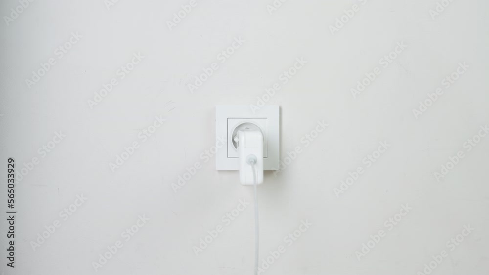 Male hand plugging and unplugging plug into white wall socket. Close-up power socket, caucasian man, charger cable Male hand plugging and unplugging plug into white wall socket. Close-up power socket, caucasian man, charger cable