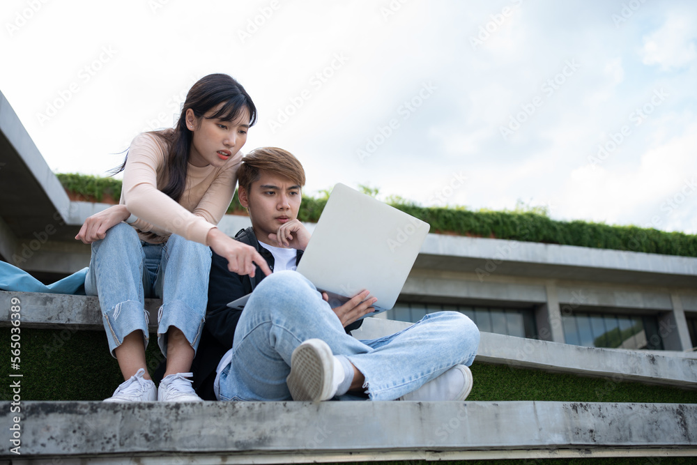 Asian students sitting on steps and use computer laptops to discuss before exams, Student lifestyle at university. Group of student do a project together Asian students sitting on steps and use computer laptops to discuss before exams, Student lifestyle at university. Group of student do a project together