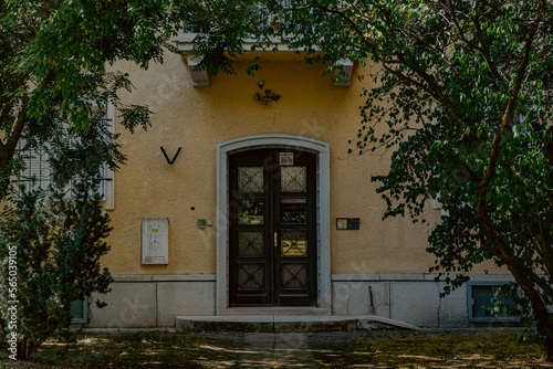 the doorway of an apartment building next to green vegetation in a shady place in budapest