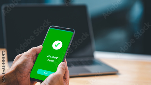 A businessman hand holds a smartphone on the screen with the message money sent transfer Concept. business, banking, financial online transactions with mobile devices. Copy space, Blurred background