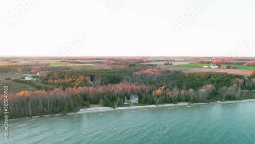 cinematic aerial of a charming lakeside cottage sorounded by a small forest, lake and beach. photo