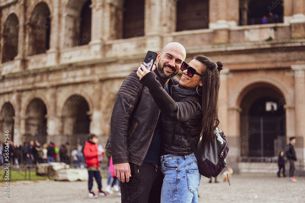 Happy  Tourists  couple traveling at Rome, Italy, poses in front of Altar of the Fatherland (Altare della Patria) and Piazza Venezia at, Rome, Italy