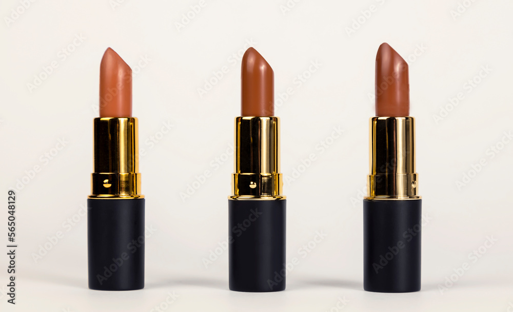 Lipsticks for lips. Three brown lipsticks of different shades on a white background. Beauty concept. Lipsticks for lips. Three brown lipsticks of different shades on a white background. Beauty concept.