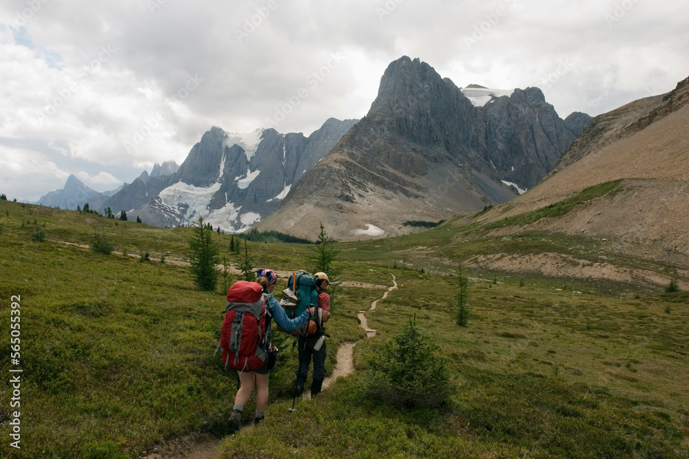 Two backpackers hike towards the towering limestone cliffs and glaciers of the Rockwall Trail, Kootenay National Park. Two backpackers hike towards the towering limestone cliffs and glaciers of the Rockwall Trail, Kootenay National Park.