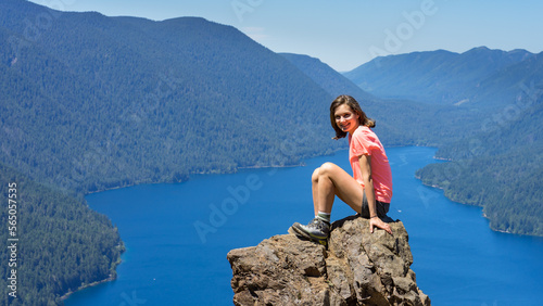 Hiker girl is on top of the mountain overlooking deep blue lake