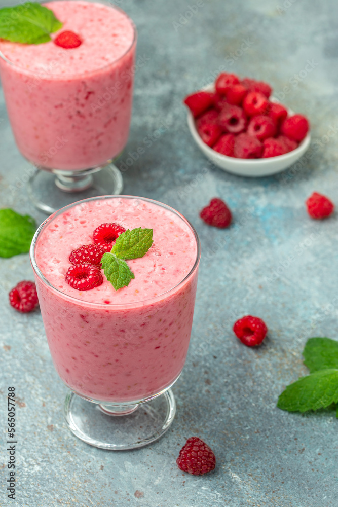 raspberries smoothie milkshake or yogurt in glass jar with berries. Yogurt cocktail on a blue background. place for text, top view raspberries smoothie milkshake or yogurt in glass jar with berries. Yogurt cocktail on a blue background. place for text, top view