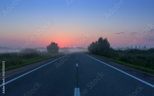 Night Misty Country Road Against Red Dawn on Blue Sky