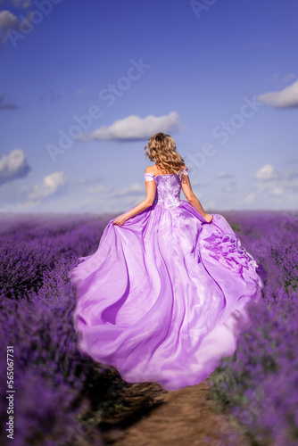 girl in a long dress runs in a lavender field. Photo from the back..