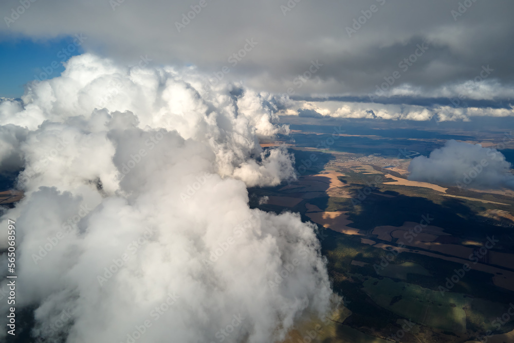 Aerial view from airplane window at high altitude of earth covered with white puffy cumulus clouds Aerial view from airplane window at high altitude of earth covered with white puffy cumulus clouds