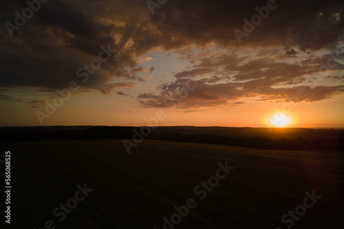 Aerial landscape view of yellow cultivated agricultural field with ripe wheat on vibrant summer evening