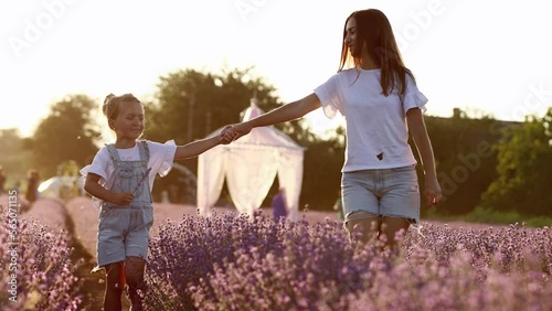 Mothers day. young mom with little child daughter holding hands and walking in a blooming lavender field. Family of two having fun and playing in meadow field on summer holiday.