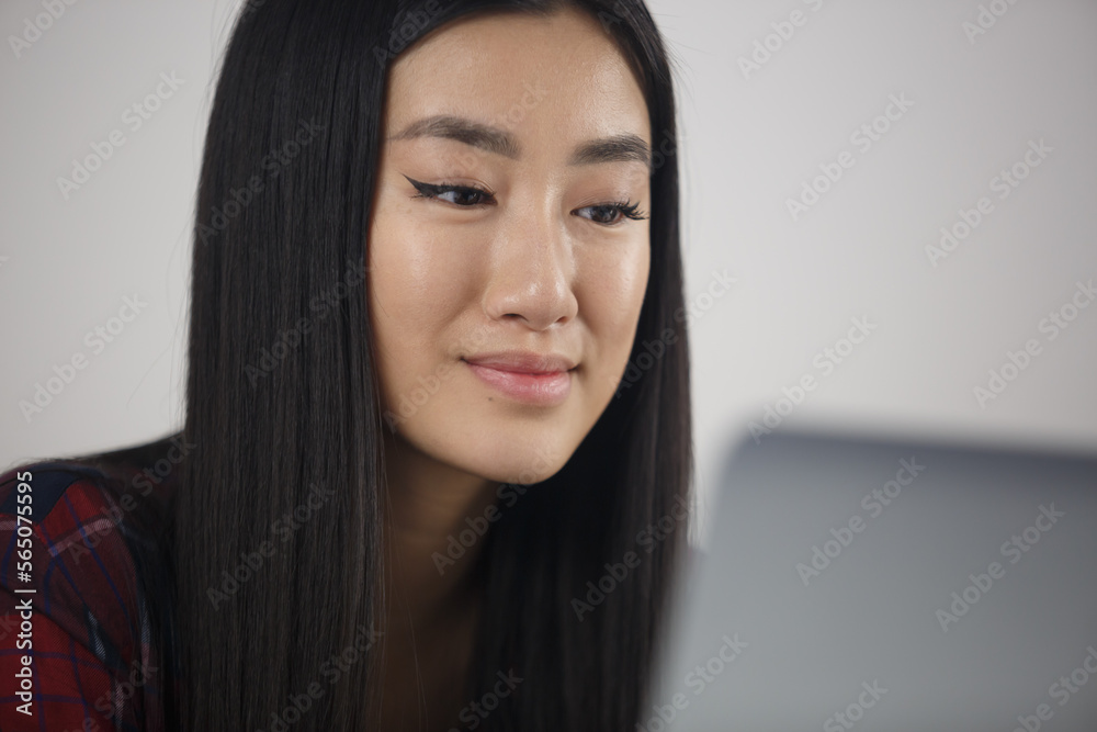 Beautiful asian girl works on laptop at home. Portrait of cheerful BIPOC Vietnamese female studying online with notebook computer Beautiful asian girl works on laptop at home. Portrait of cheerful BIPOC Vietnamese female studying online with notebook computer