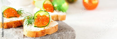 Toast with soft cheese, cucumber, red caviar and fennel on a stone plate. Copy space