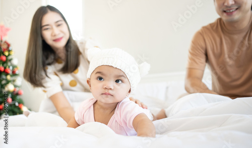 Smiling mother and father holding their newborn baby daughter at home. portrait of Asian family in bed room.