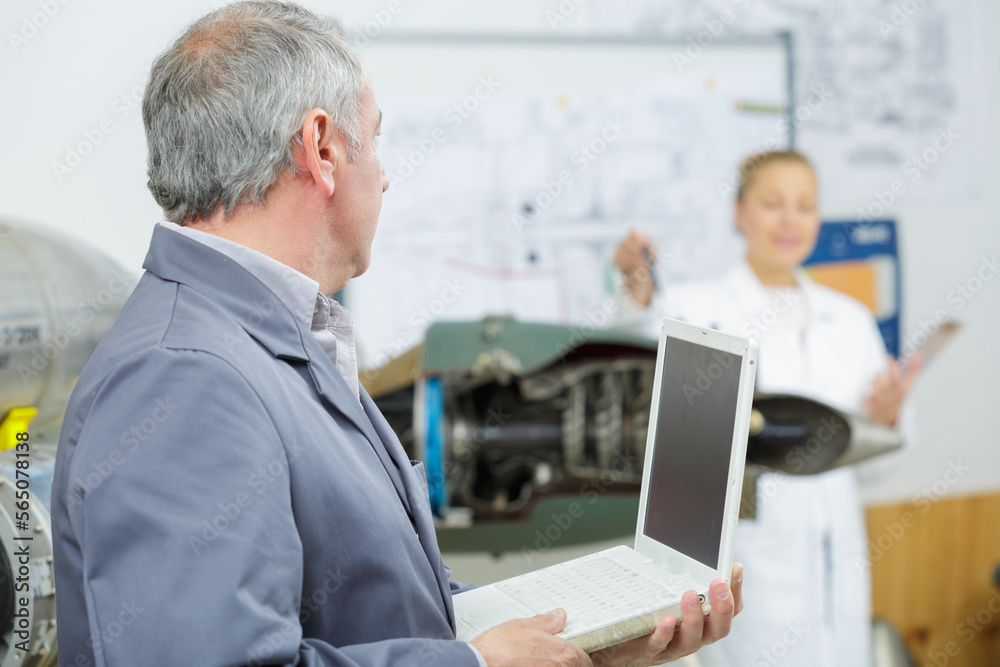 side view of mature male technician using laptop in workshop side view of mature male technician using laptop in workshop
