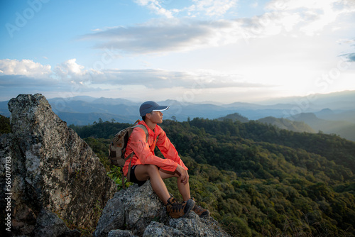 Young man with a backpack enjoying the sunset on the top of the mountain Travel traveler on valley scenery mockup background Mountain climbers watch the sunlight shining on their country journey.
