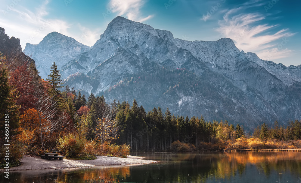 Obraz premium Scenic landscape during sunset. Atmospheric colorful landscape with calm lake in mountain valley and rocky mount on background. View on lake, trees and rocks mountains under sunlight. Almsee lake