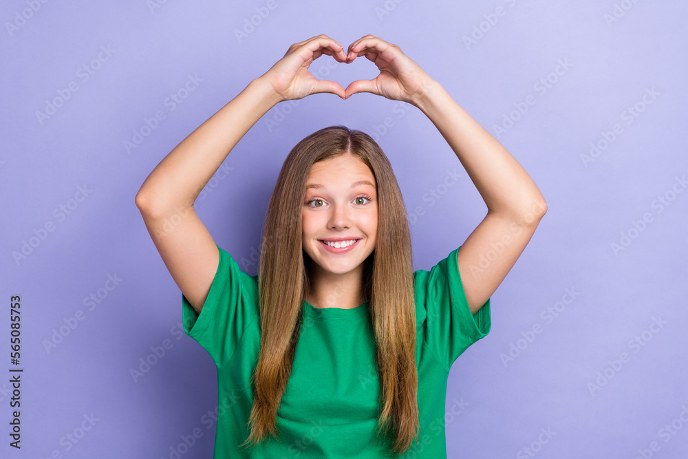 Photo of glad adorable cute lady wear green stylish clothes arms up fingers make heart figure isolated on purple color background Photo of glad adorable cute lady wear green stylish clothes arms up fingers make heart figure isolated on purple color background