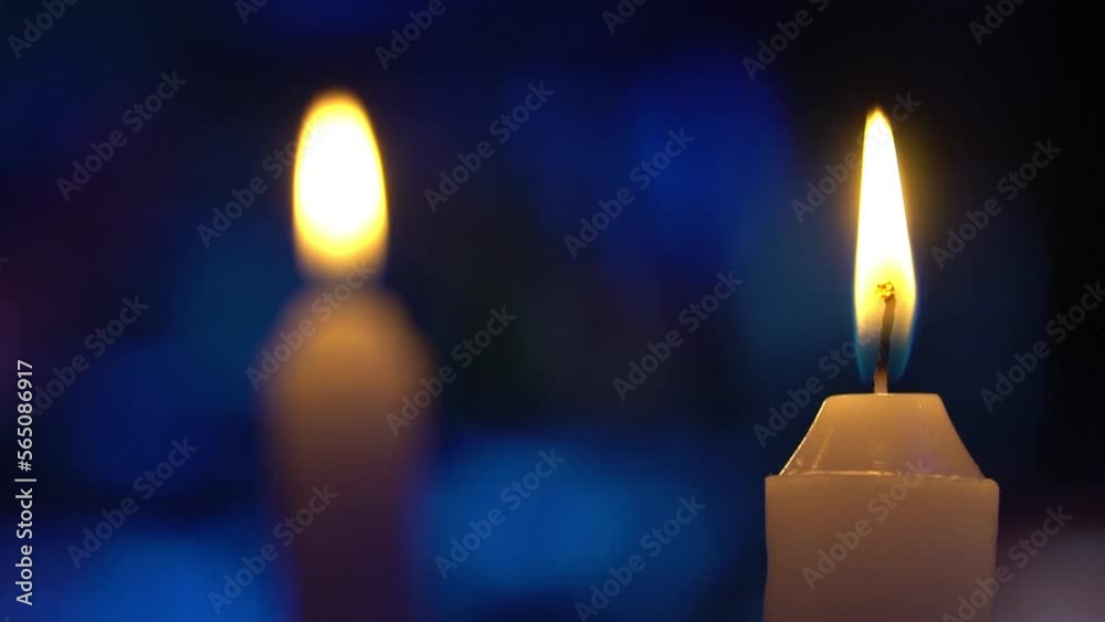 Velas acesas com fundo azul desfocado, com luzes formando desenhos abstratos em movimento, projetados sobre este fundo