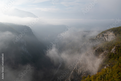 Mountain viewpoint over river canyon obscured in fog and clouds during autumn morning, misty mountain landscape