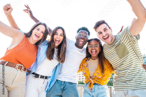 Φωτογραφία Low angle view of a happy group of multiracial friends having fun and looking at camera , enjoying outdoors